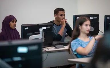 三个学生在教室里玩电脑 