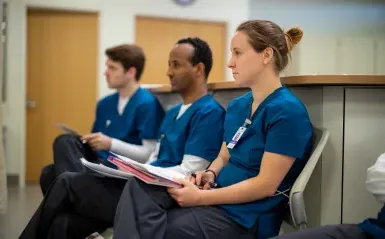 three nursing students sitting taking notes 