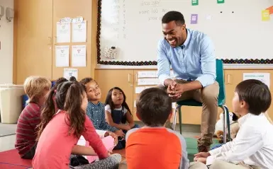 male teacher surrounded by elementary students 