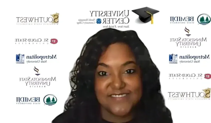 woman smiling in front of wall of university logos 